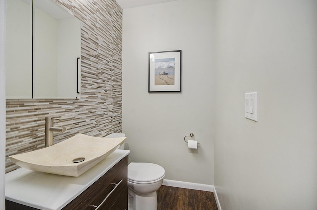 bathroom featuring tasteful backsplash, toilet, vanity, wood finished floors, and baseboards