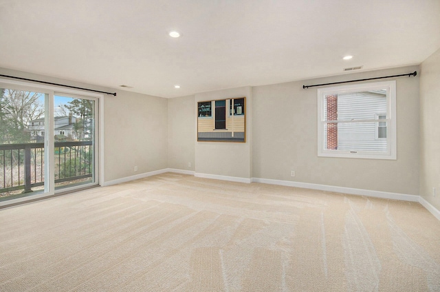 empty room with plenty of natural light, baseboards, and light colored carpet