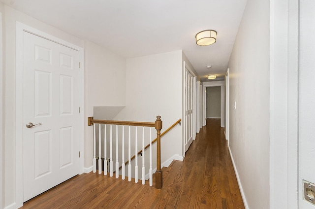 hall featuring baseboards, an upstairs landing, and wood finished floors