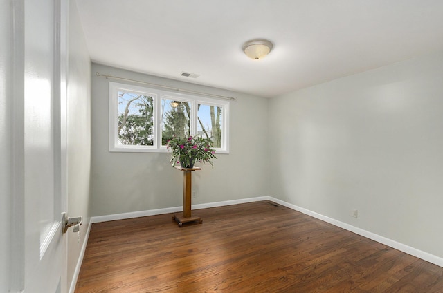 empty room with baseboards, visible vents, and dark wood-style flooring