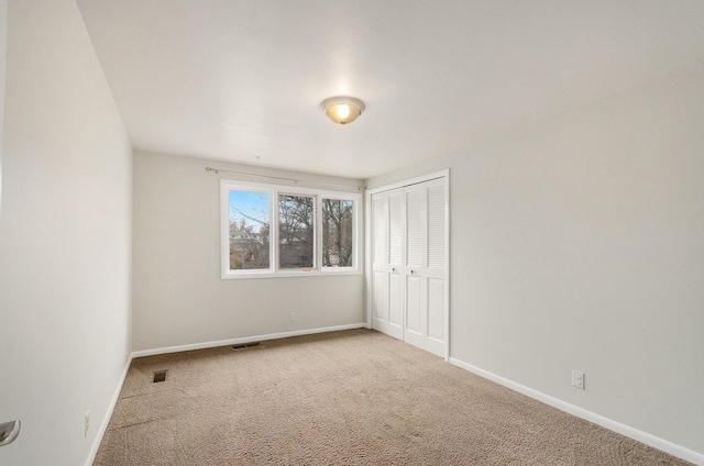 unfurnished bedroom with a closet, carpet flooring, visible vents, and baseboards