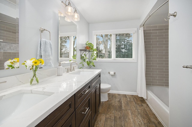 bathroom with toilet, double vanity, a sink, and wood finished floors