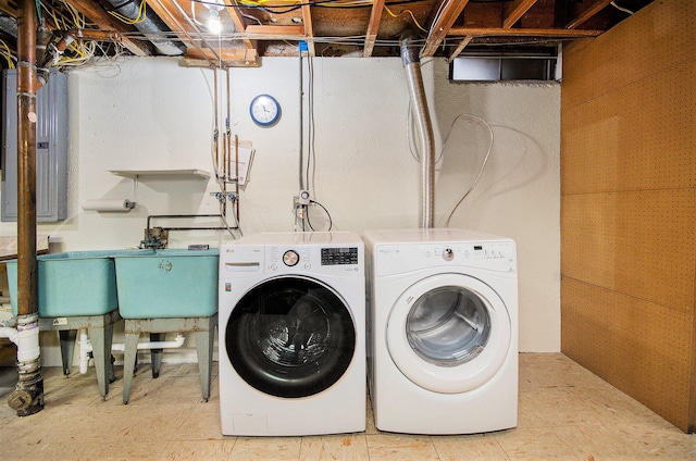 laundry room featuring laundry area, washing machine and dryer, electric panel, and a sink