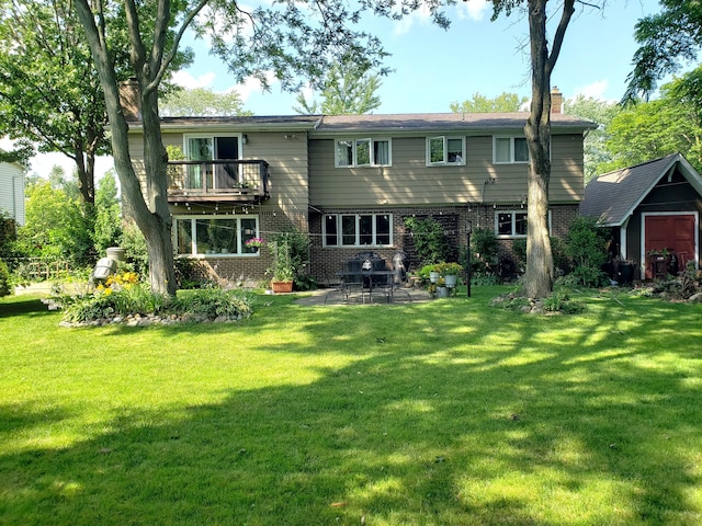 back of house featuring a balcony, a yard, a chimney, and brick siding