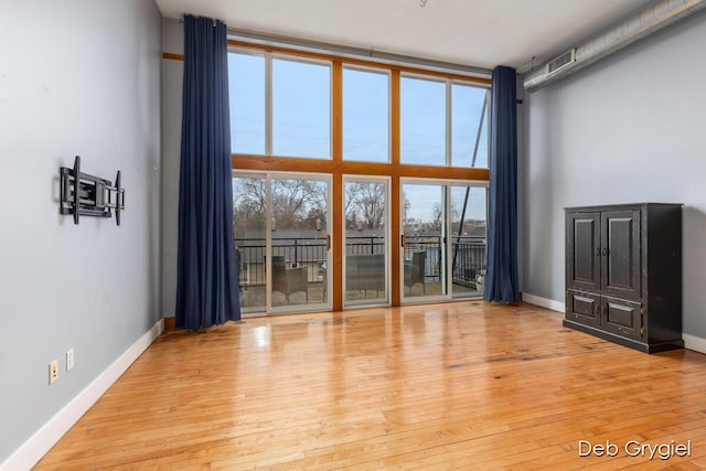 interior space featuring a towering ceiling, baseboards, and hardwood / wood-style floors