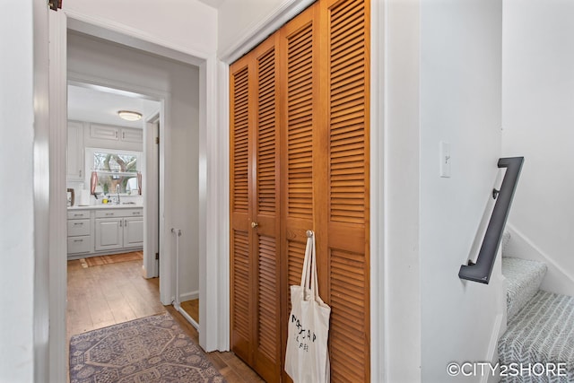 hallway featuring stairs, a sink, baseboards, and hardwood / wood-style flooring