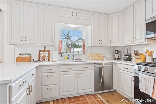 kitchen with stainless steel appliances, a sink, light countertops, and white cabinets