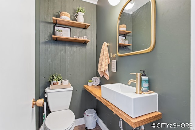 half bathroom featuring toilet, baseboards, and a sink