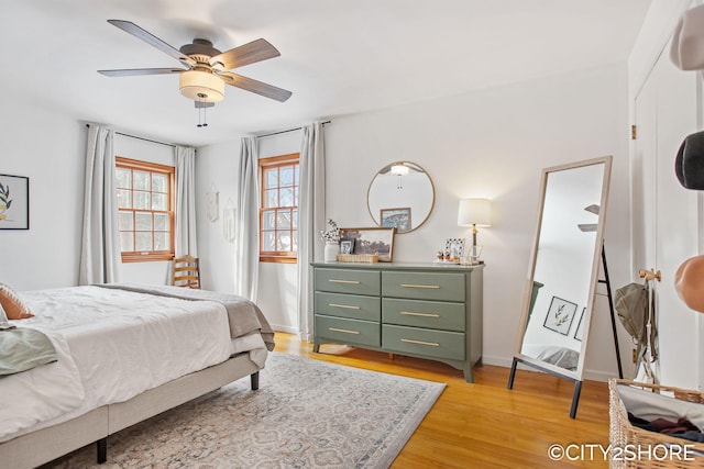 bedroom with light wood-type flooring, a ceiling fan, and baseboards