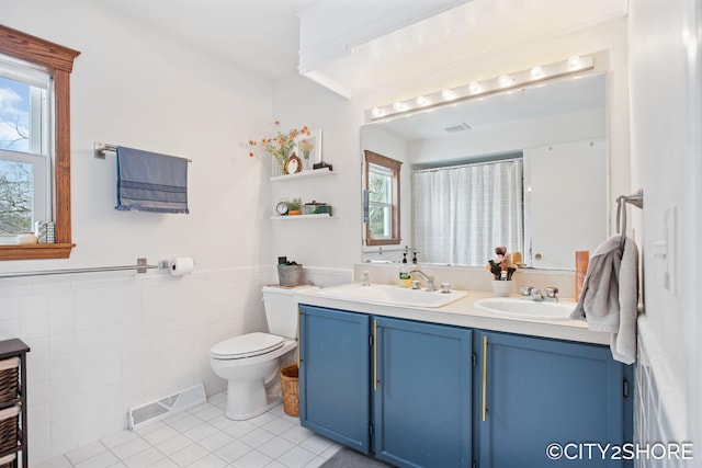 bathroom featuring a wainscoted wall, visible vents, a sink, and toilet