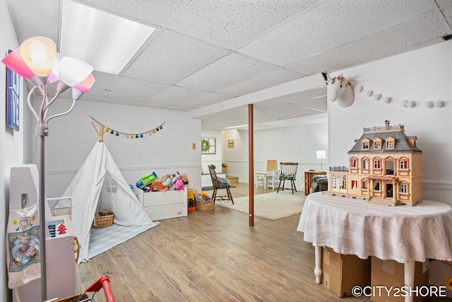 recreation room with a paneled ceiling and wood finished floors