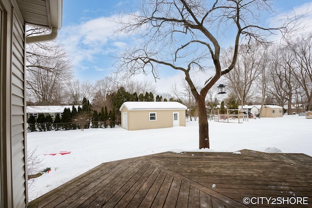 snow covered deck with a storage shed, an outdoor structure, and fence