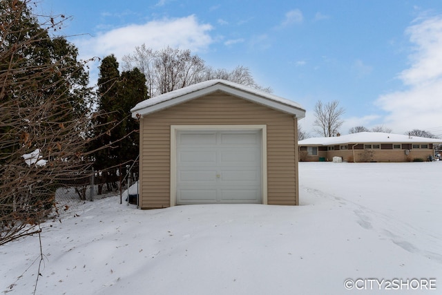 snow covered garage with a detached garage