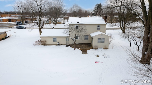 snow covered back of property with a chimney