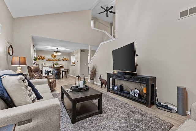 living room featuring visible vents, baseboards, ceiling fan, wood finished floors, and high vaulted ceiling