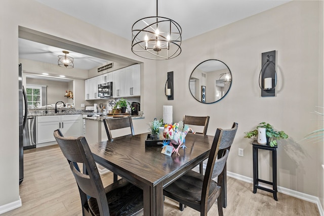 dining space featuring light wood-type flooring, an inviting chandelier, and baseboards