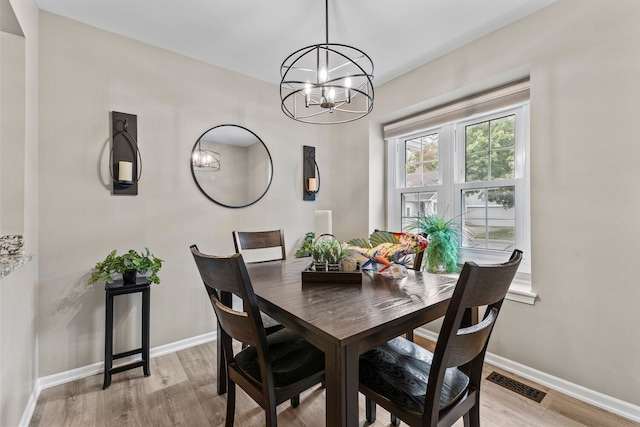 dining area with light wood-style floors, visible vents, a notable chandelier, and baseboards