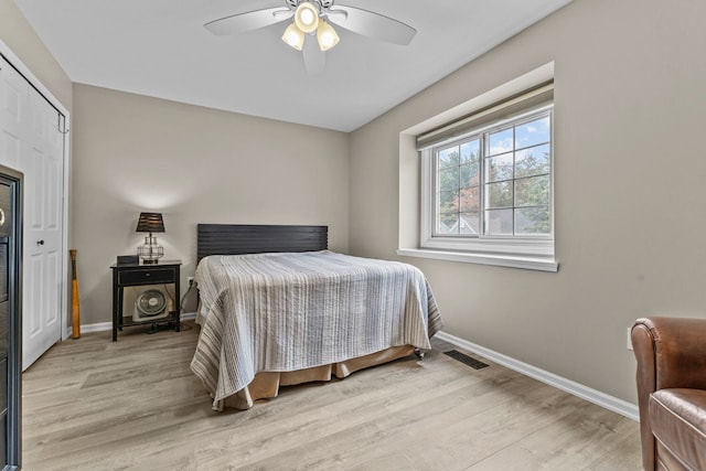 bedroom featuring light wood finished floors, a closet, visible vents, ceiling fan, and baseboards