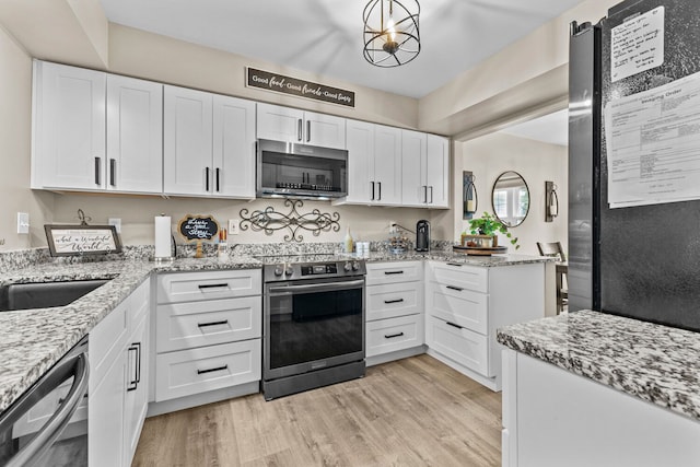 kitchen with appliances with stainless steel finishes, white cabinetry, light wood-style flooring, and light stone countertops