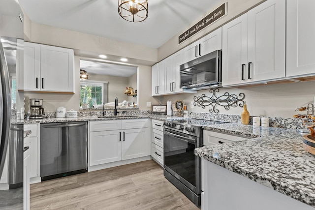 kitchen featuring light wood-style floors, white cabinetry, stainless steel appliances, and a sink