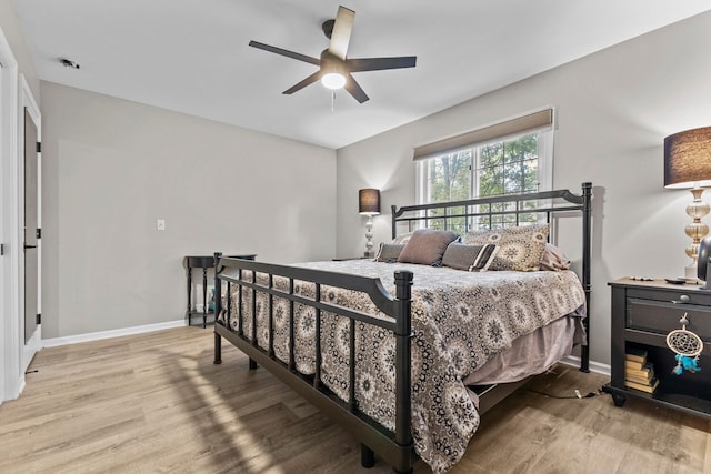 bedroom featuring a ceiling fan, baseboards, and wood finished floors