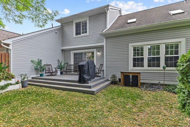 back of house featuring a shingled roof, a yard, and a wooden deck