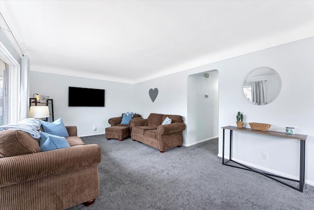 carpeted living area with arched walkways and baseboards