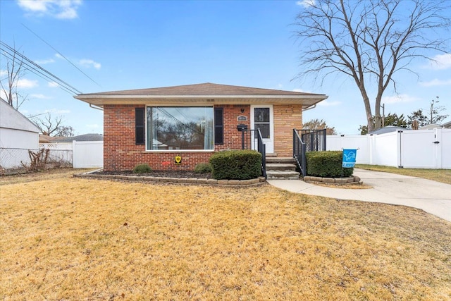 bungalow-style home featuring brick siding, fence, driveway, a gate, and a front lawn