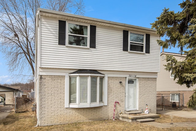 view of front of house featuring brick siding and fence