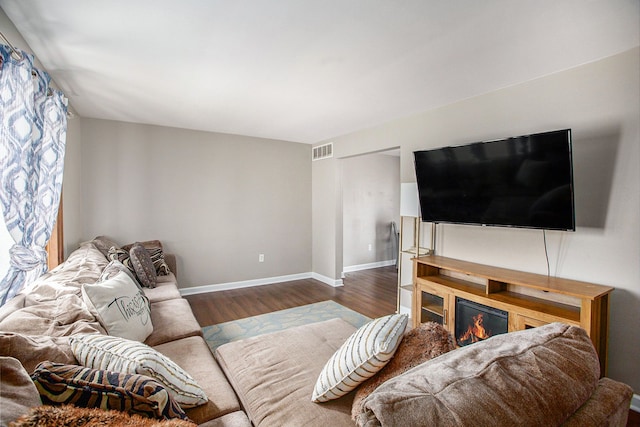 living room featuring wood finished floors, visible vents, and baseboards