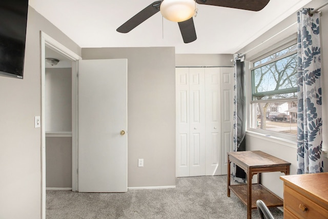 interior space featuring light colored carpet, baseboards, and a ceiling fan