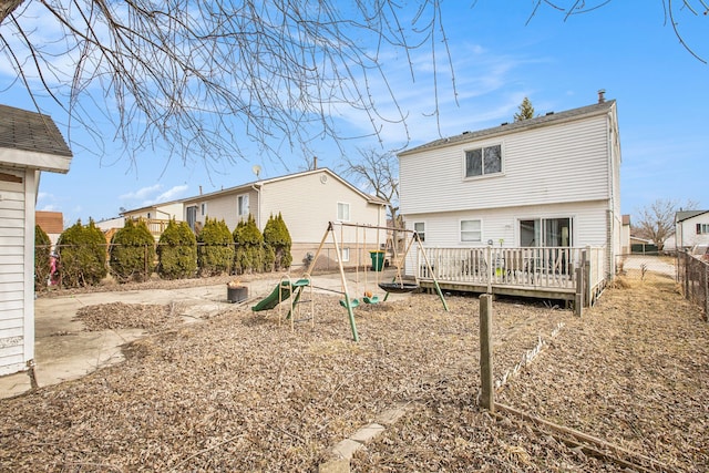 back of property with a playground, a fenced backyard, and a wooden deck