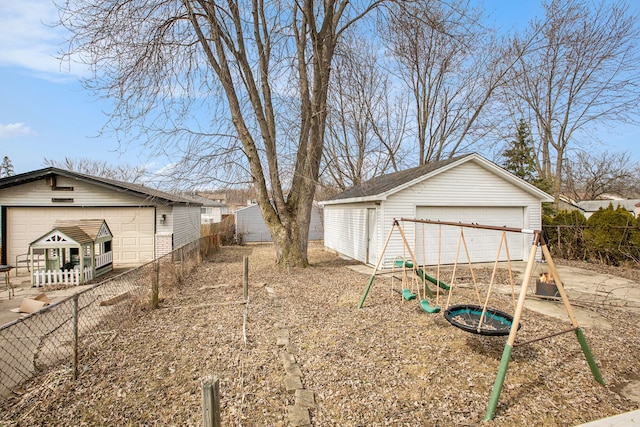 view of yard with a garage, a playground, an outdoor structure, and fence