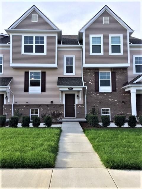 view of front of home with brick siding and a front yard