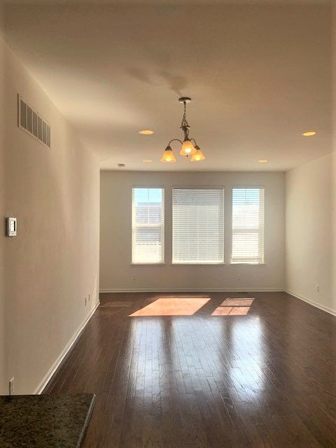 empty room featuring visible vents, baseboards, dark wood-type flooring, and a chandelier