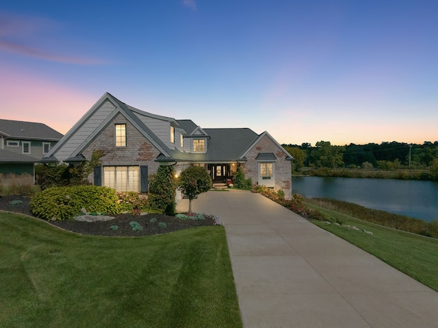 view of front of property with a front yard, a water view, and driveway