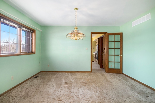 carpeted spare room with visible vents and baseboards