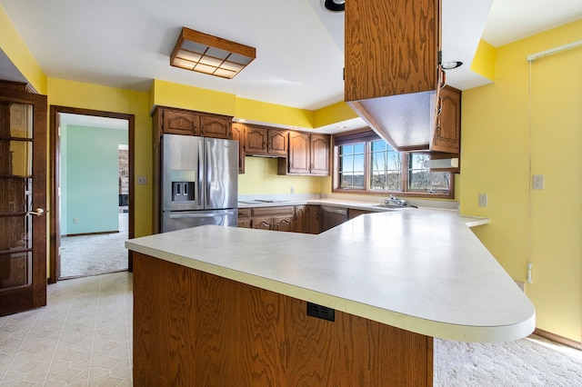 kitchen featuring a peninsula, stainless steel fridge with ice dispenser, and light countertops