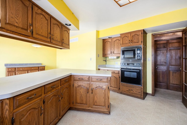 kitchen featuring built in microwave, brown cabinetry, light countertops, and oven