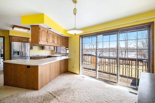 kitchen with visible vents, decorative light fixtures, stainless steel fridge, a peninsula, and light colored carpet