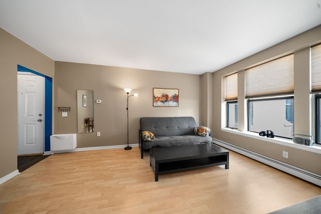 sitting room featuring light wood finished floors, a baseboard radiator, and baseboards