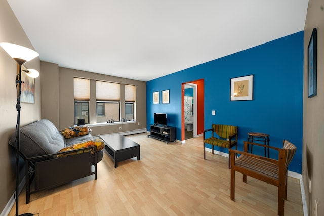 living room with an accent wall, light wood-type flooring, baseboards, and baseboard heating