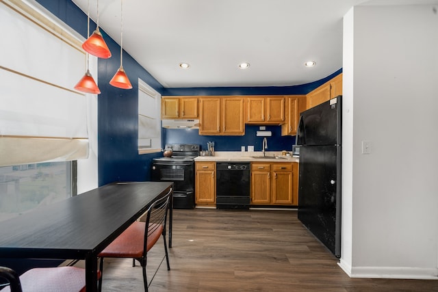 kitchen with dark wood-type flooring, under cabinet range hood, light countertops, black appliances, and a sink