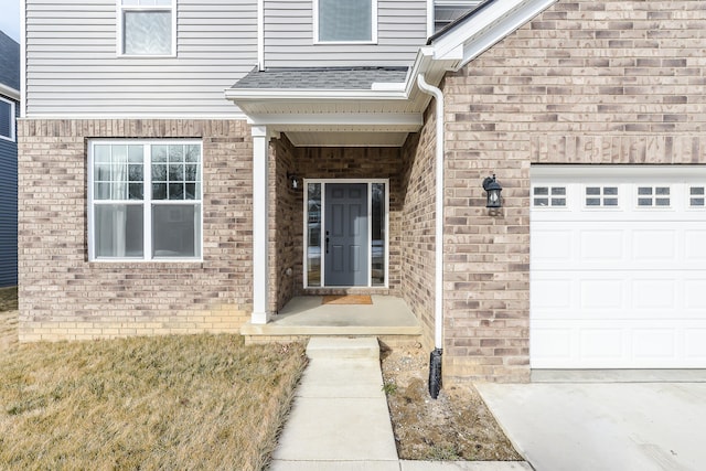 entrance to property featuring an attached garage, a shingled roof, and brick siding