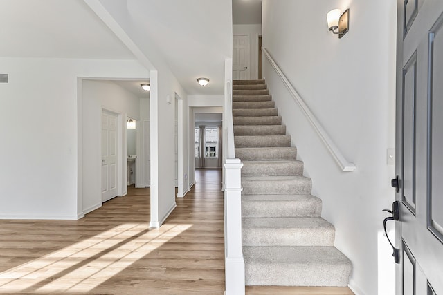 foyer featuring visible vents, baseboards, stairway, and light wood finished floors