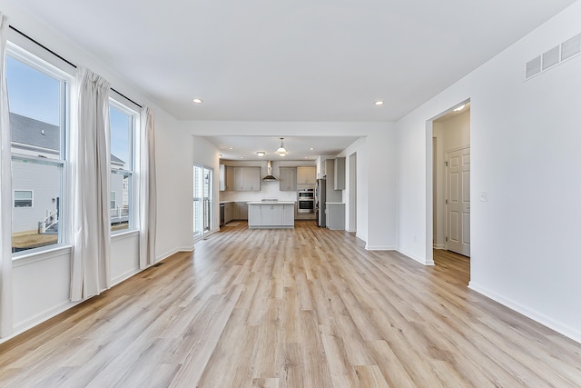 unfurnished living room with light wood finished floors, baseboards, visible vents, and recessed lighting