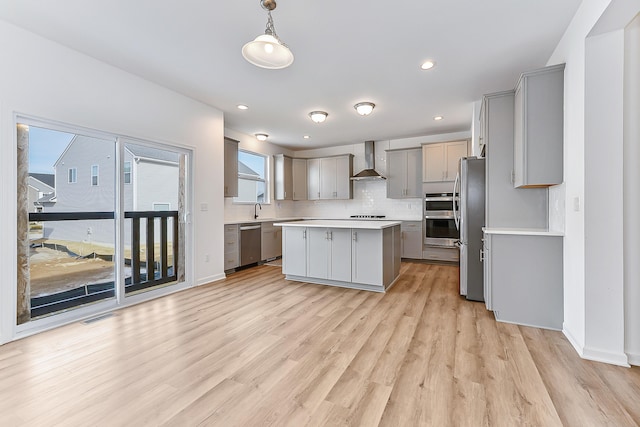 kitchen featuring wall chimney exhaust hood, appliances with stainless steel finishes, a sink, and gray cabinetry