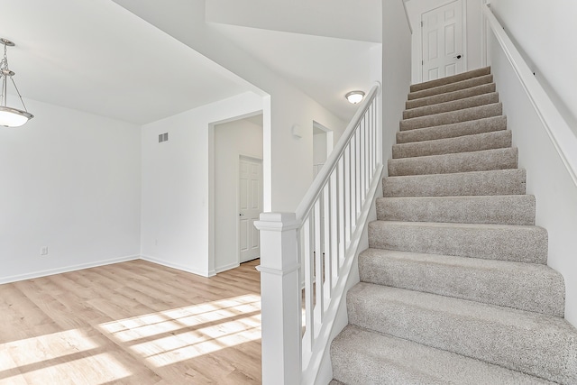 stairway with wood finished floors, visible vents, and baseboards