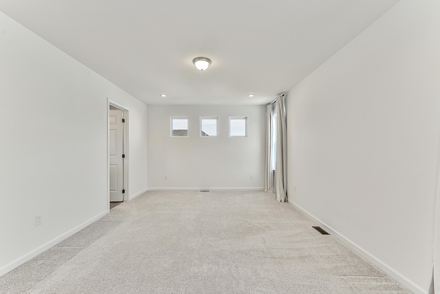 empty room featuring baseboards, visible vents, and light colored carpet