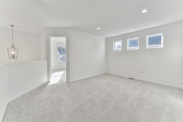 empty room with recessed lighting, light carpet, baseboards, and an inviting chandelier